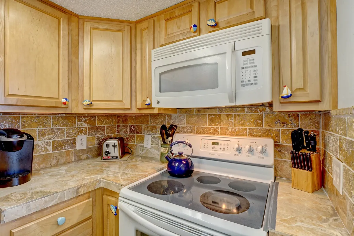 A homey kitchen angle featuring a kettle on the stove, a countertop with a toaster, and various kitchen utensils. The layout and accessories emphasize both functionality and the warmth of a space designed for cooking and entertaining.