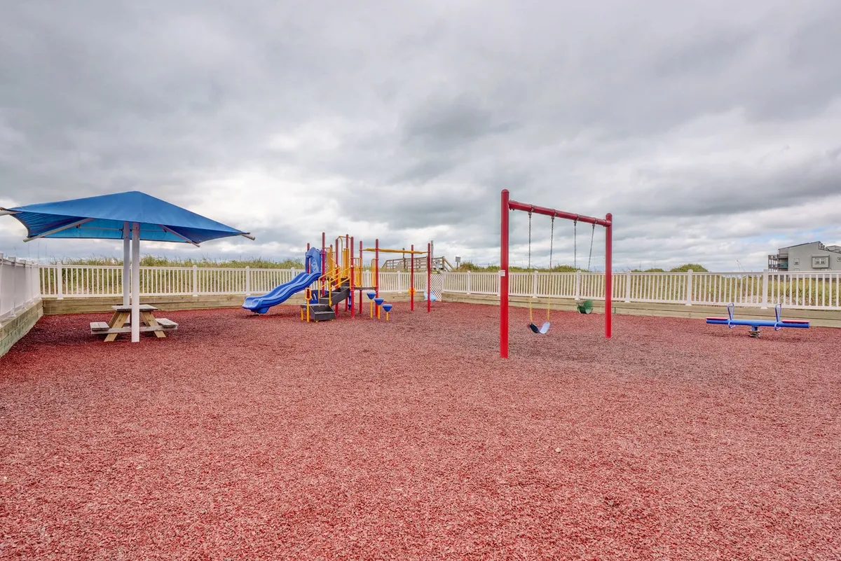 A joyful outdoor scene featuring a well-equipped playground with swings and a shade structure, surrounded by green space. Children are shown playing, creating the perfect setting for family outings and carefree play.